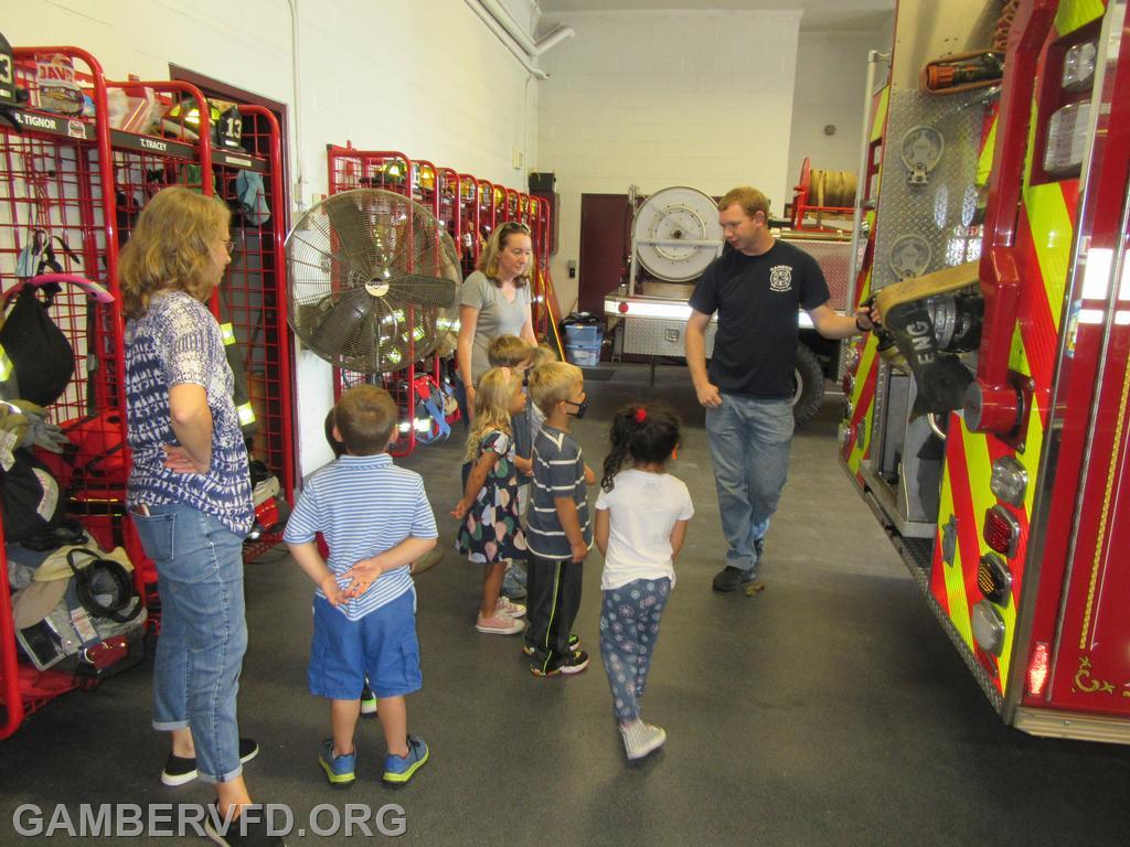 Firefighter Sgt. Sean Baldwin shows a small group of preschoolers some of the equipment on a fire engine.