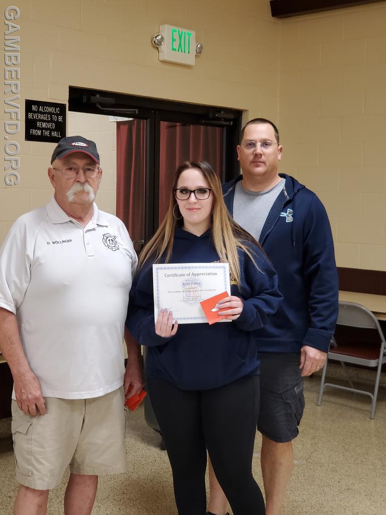 Rylie Fuller accepts  a certificate for having the second highest number of EMS responses in 2021. President Dale Bollinger (L) and 1st Vice President/Captain Chad Hastings presented the award.