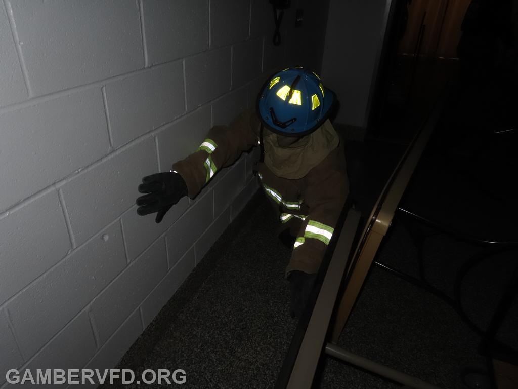 A junior firefighter proceeds through the training maze. Lights were off and their face was covered so they had to feel their way.